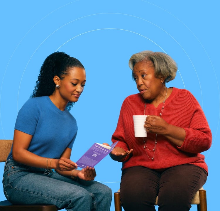 Photo of an African-American young woman siting with an older African-American woman who is in a COVID-19 high-risk group reviewing a brochure.