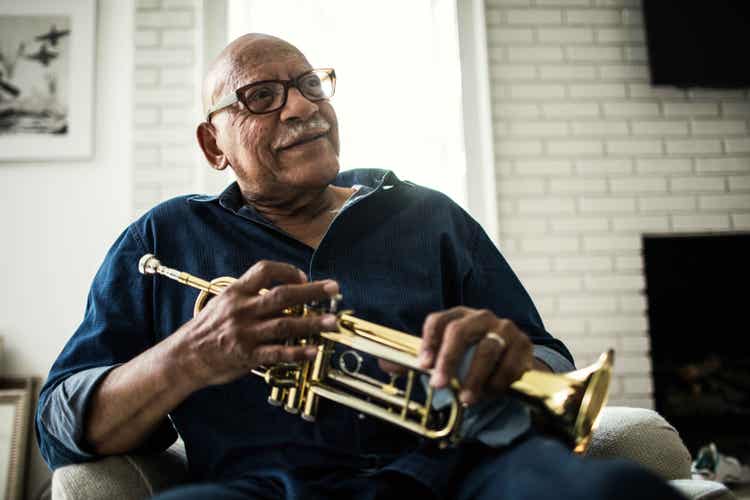 Photo of older African-American man with COVID-19 high risk factors playing his trumpet.