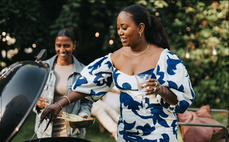 Two African-American women with COVID-19 high-risk factors grilling outside.