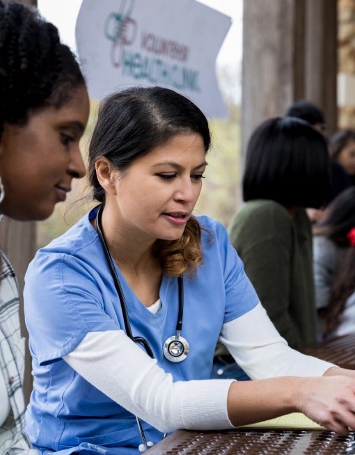 Photo of a young Latina nurse speaking to a young African-American woman about the COVID-19 impact on the Black community.